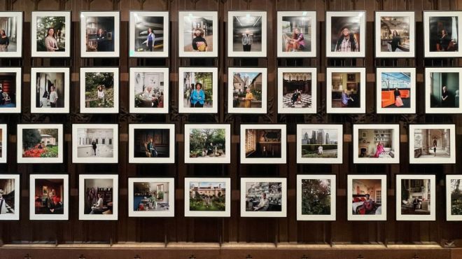 50 framed portrait photographs of women against a dark wood panelled background