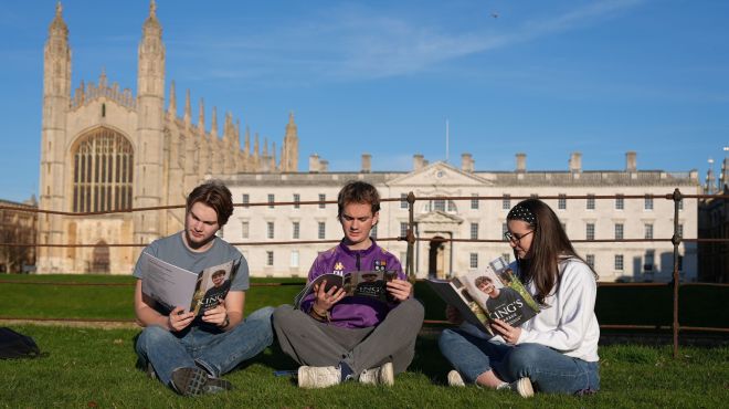 Students sat on the grass reading magazine 