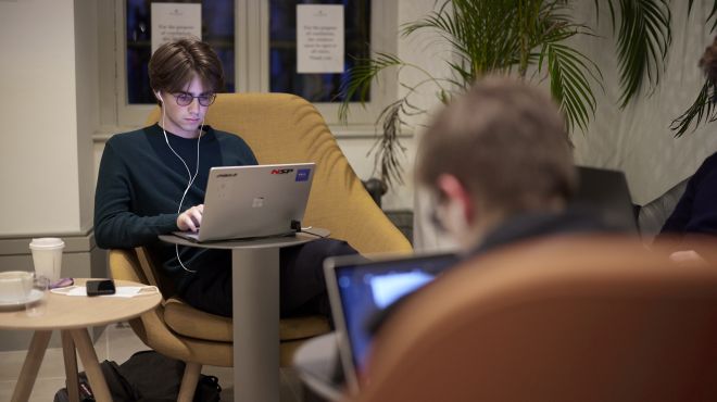 Student typing on his laptop in the College bar