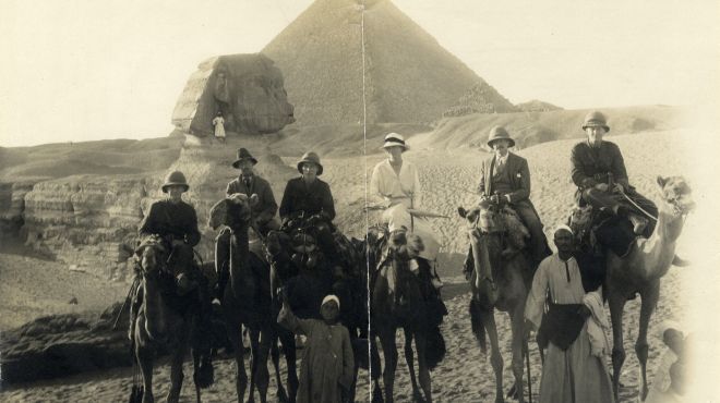 old image of people on horse in front of pyramids