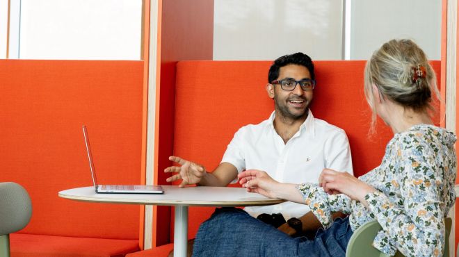 Two graduate students sitting on an orange sofa
