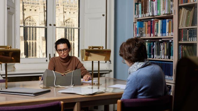 Two graduate students reading in the archives