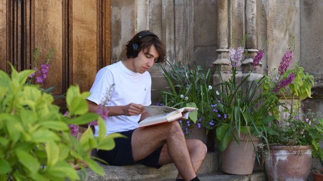 Student sat reading a book on stone steps