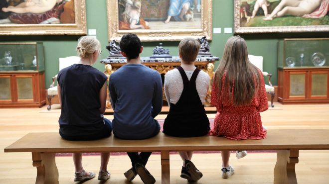 students sit on a bench in a museum gallery