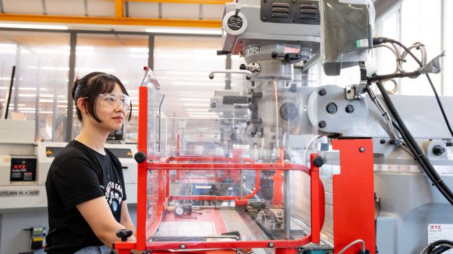 a female student operates engineering machinery in a laboratory