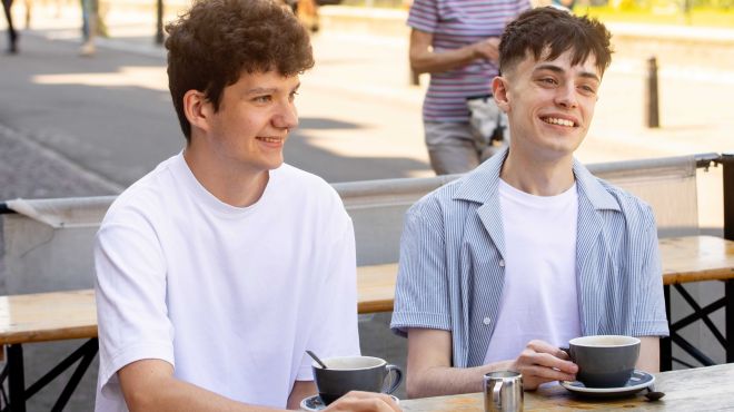 Two students smiling with coffee cups