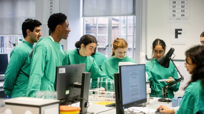 a group of students wearing protective clothing undertake a practical session in a pathology lab