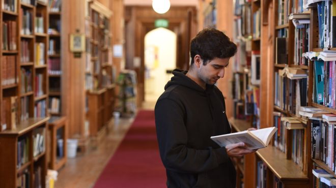 a male student reads a book in a library