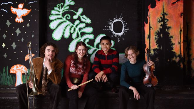 student musicians sit on the edge of a stage