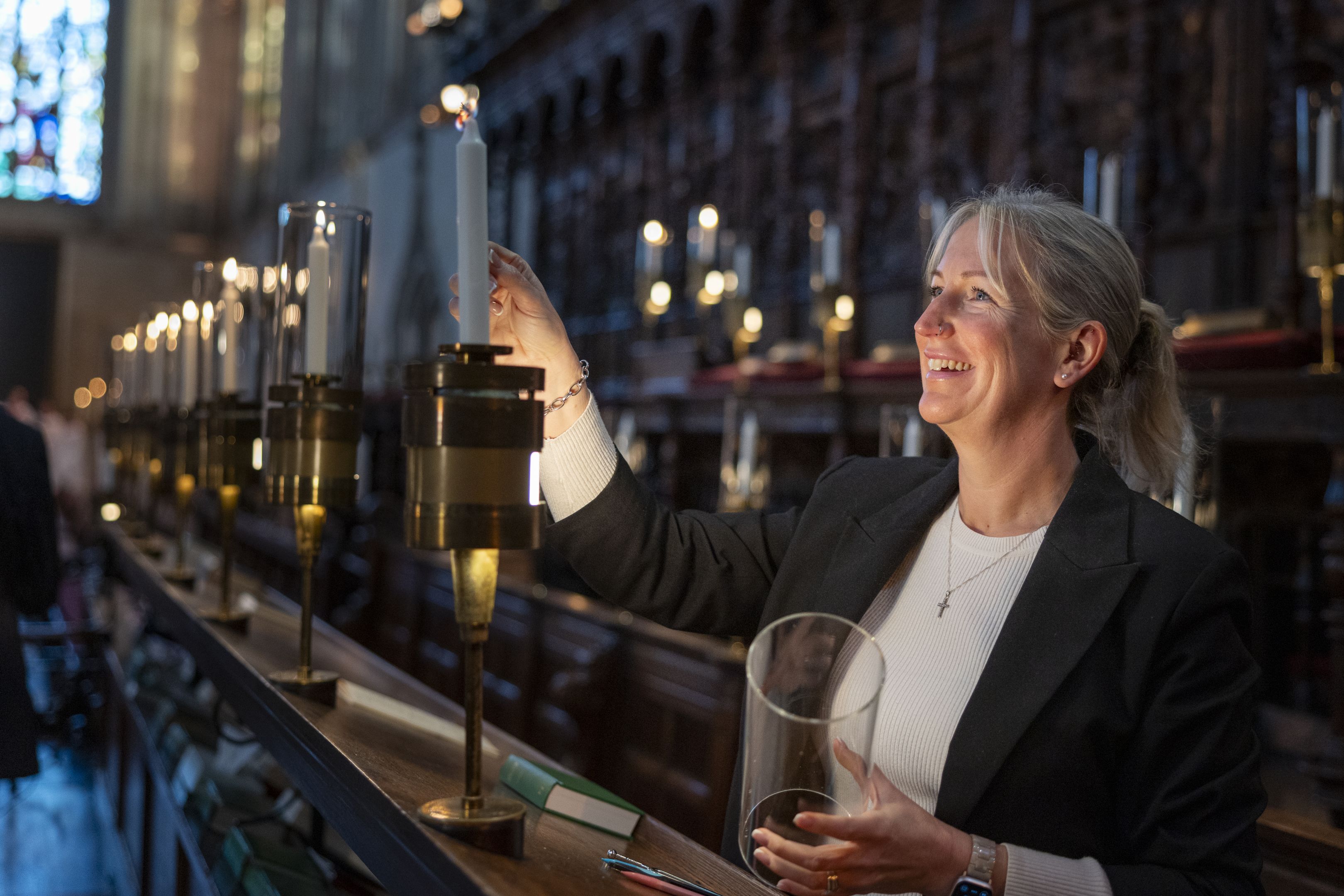 A wonman lighthing candles during a rehearsal for the Festival of Nine Lessons.