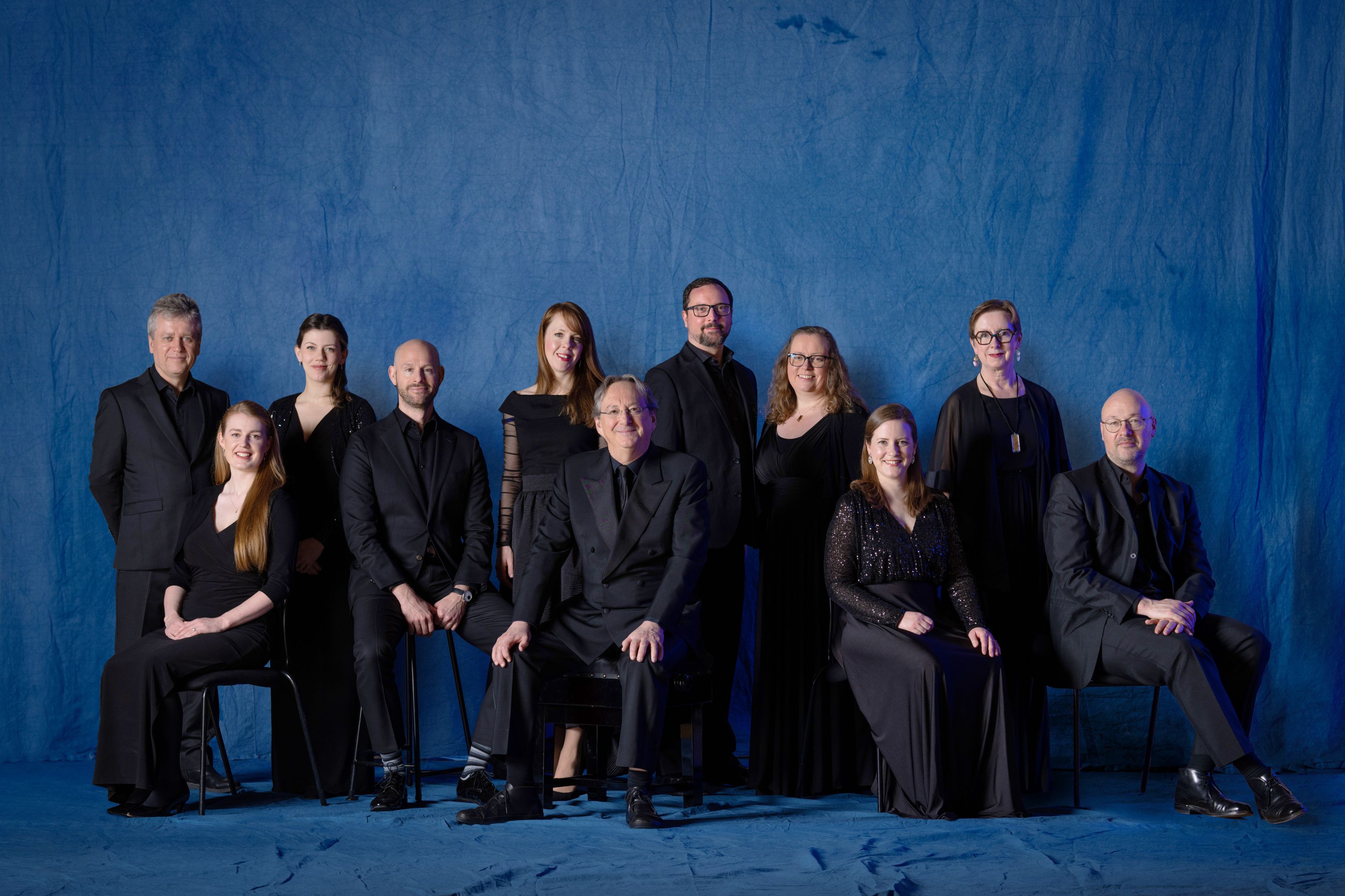 A group of singers wearing black against a blue background