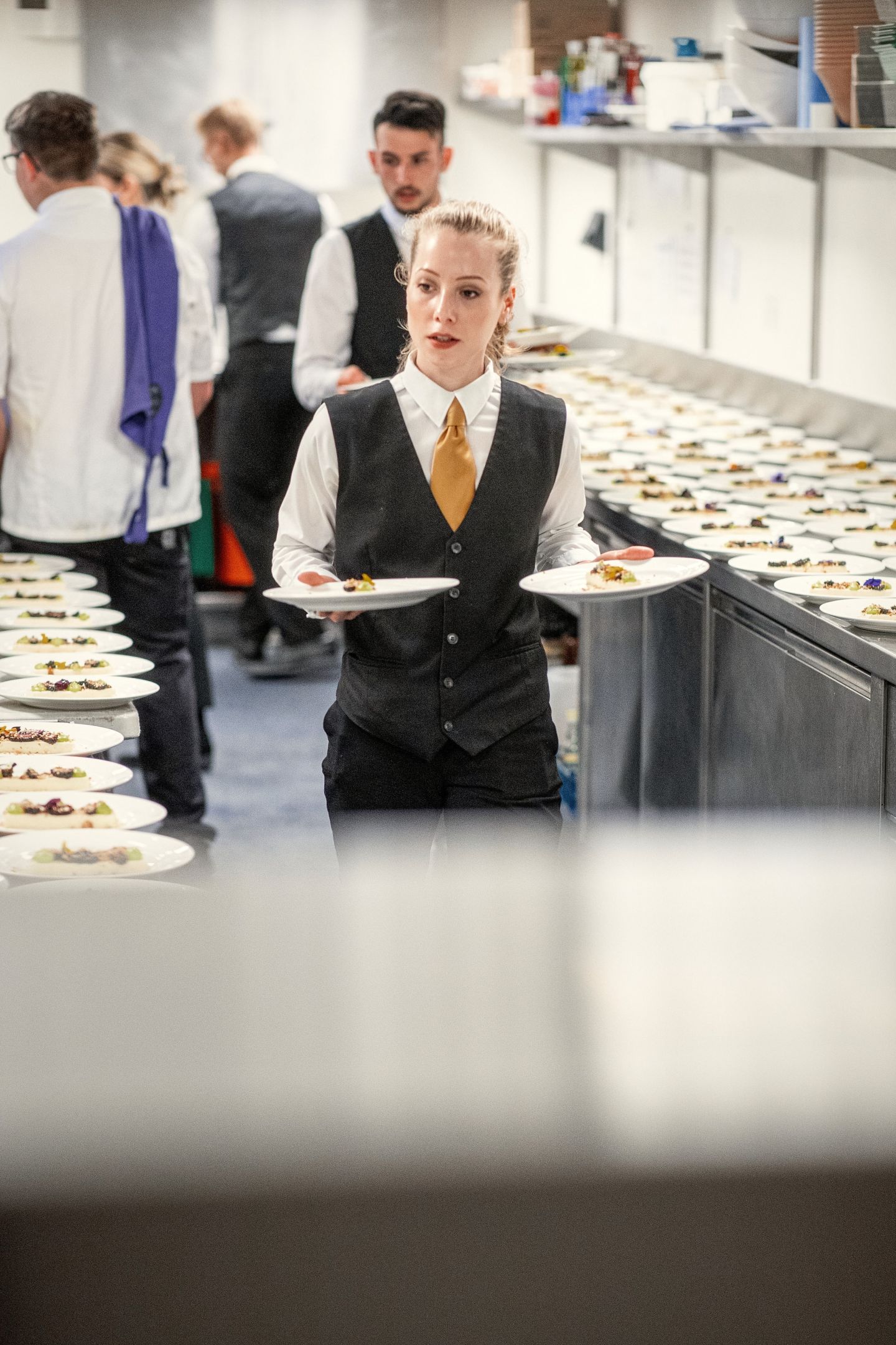 A member of the catering team prepares to serve the next course a waitress carrying plates to be served to diners