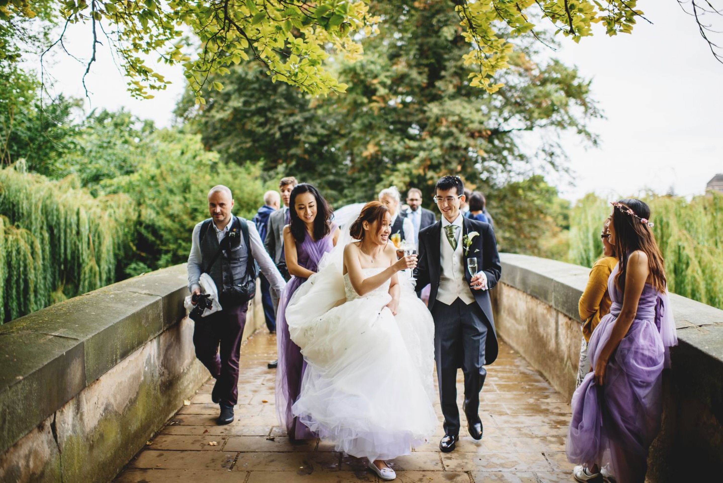 a bride and groom on a stone bridge with their wedding party