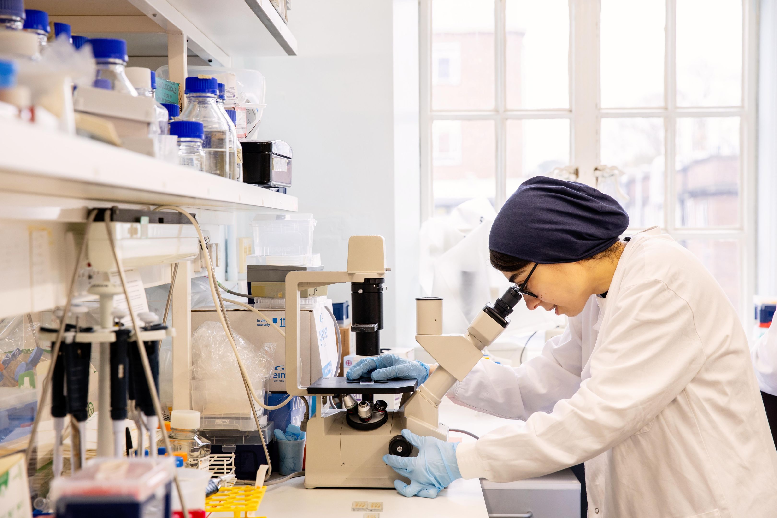 a researcher looking into a microscope