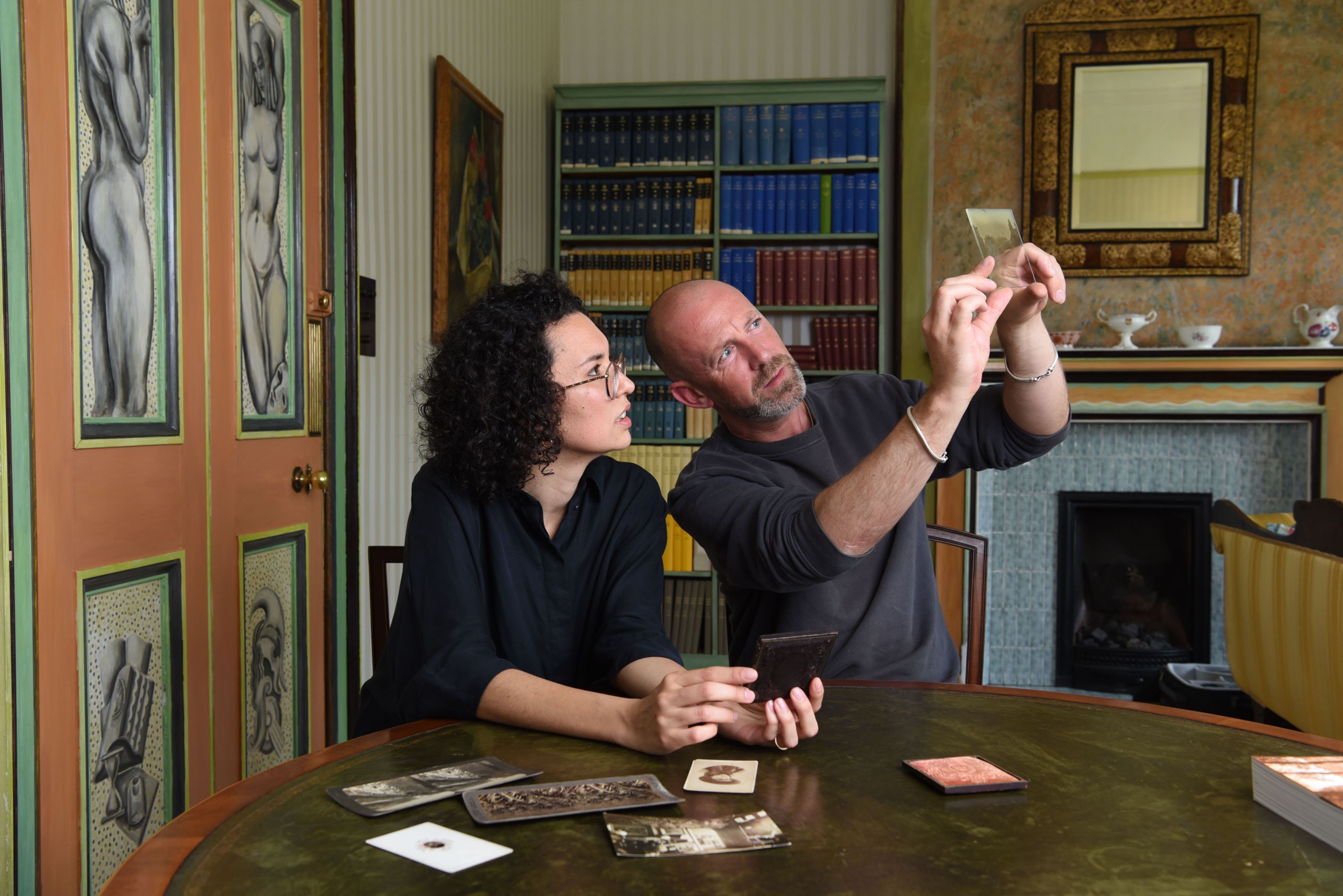 A woman and a man looking at vintage photographs