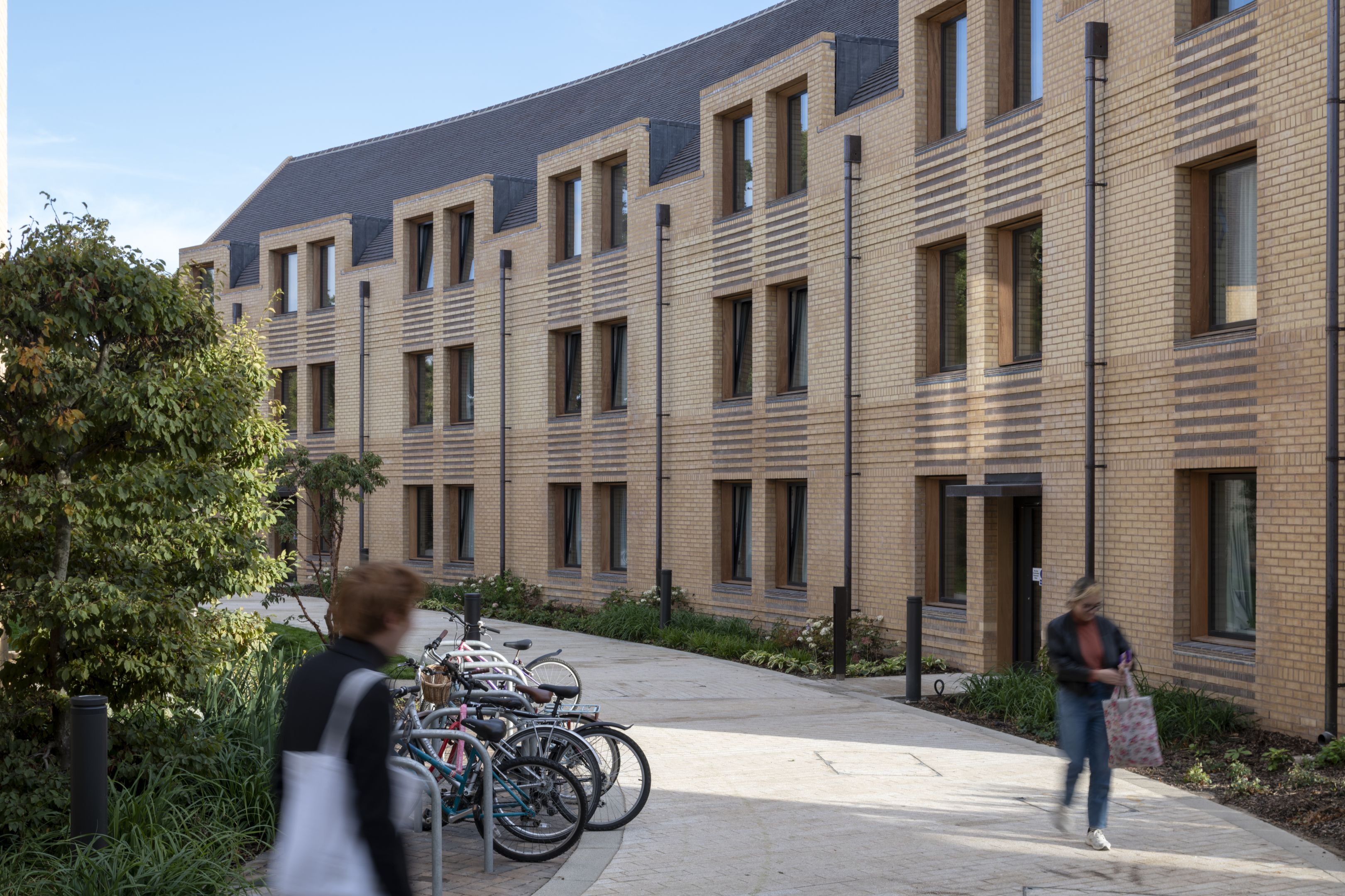 A modern accommodation building with hedges, student and bike storage