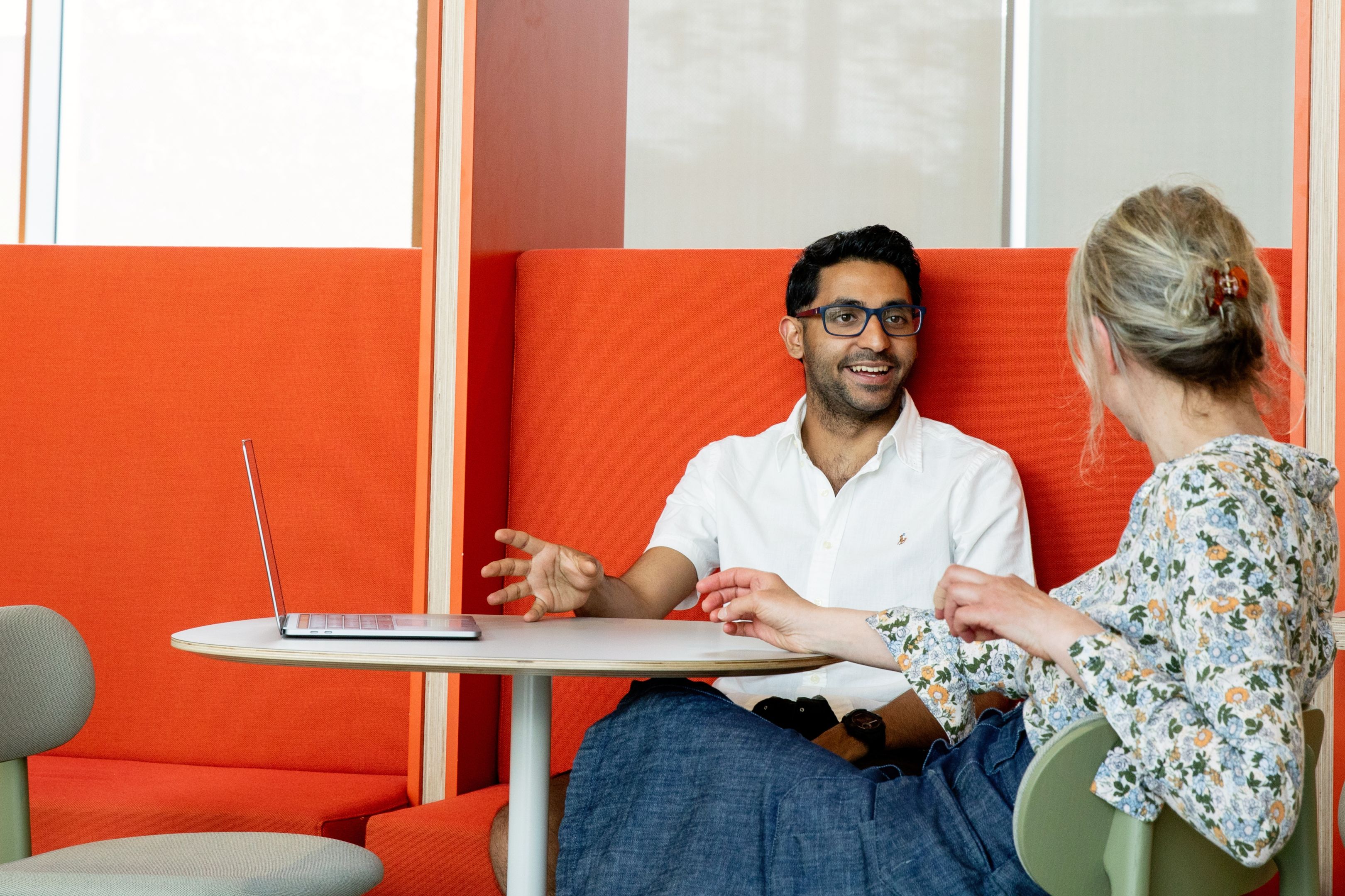 Two graduate students sitting on an orange sofa