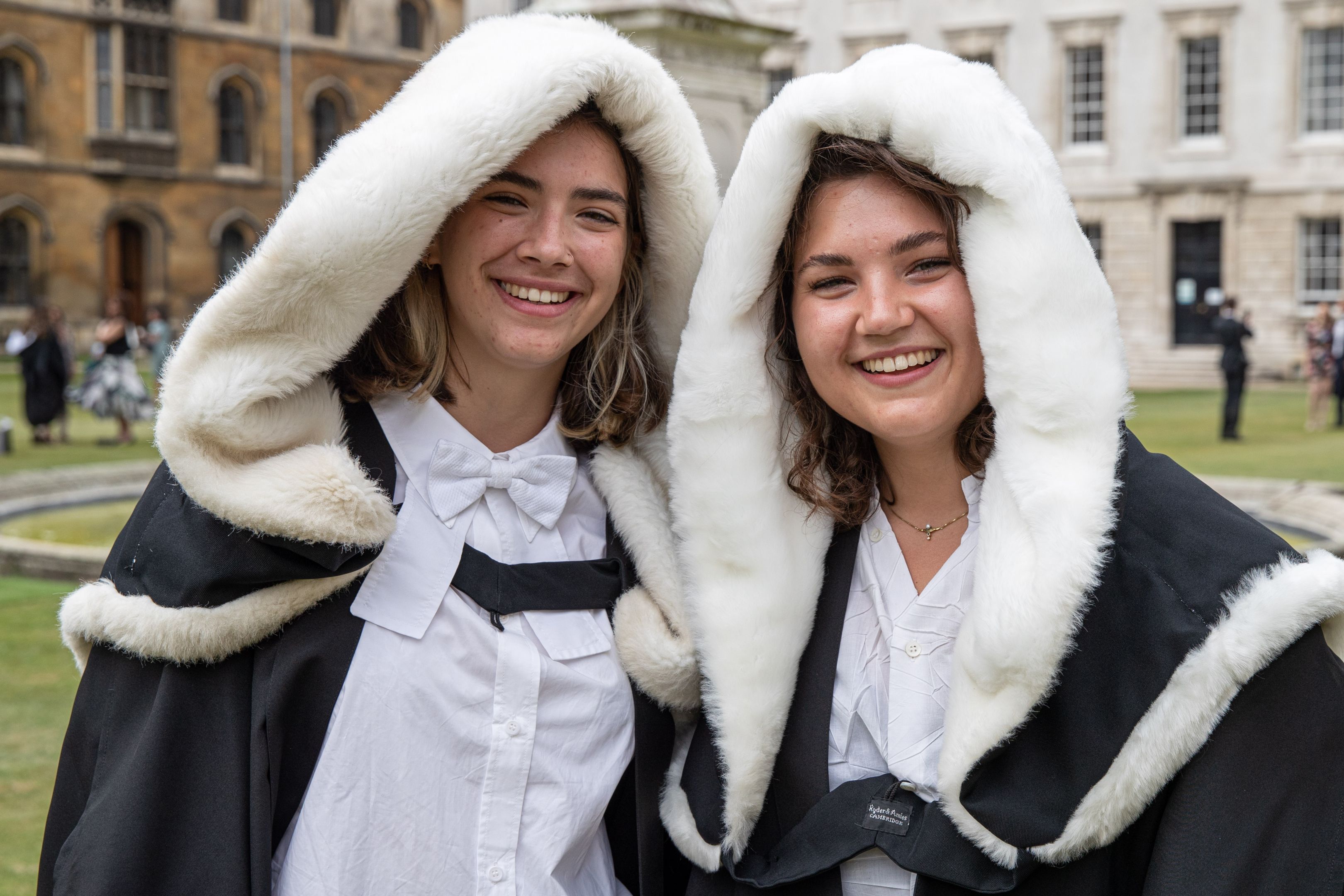 Two female students smiling wearing hoods