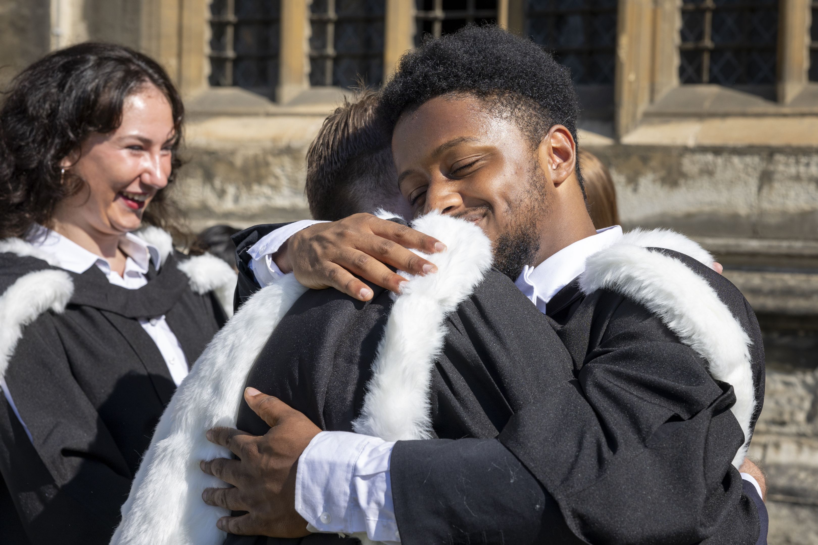 Two students hugging wearing academic gowns