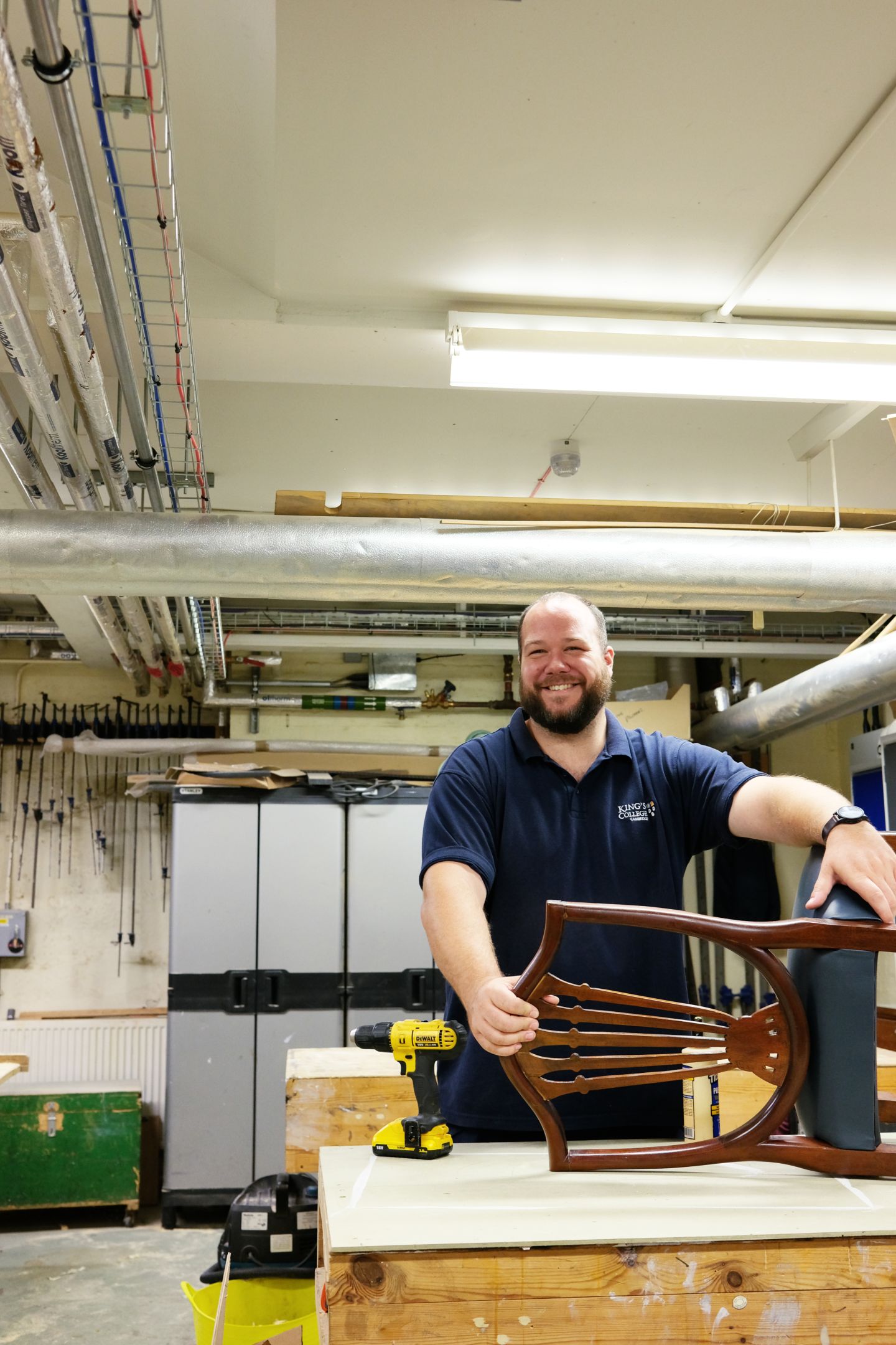 Man standing in a workshop repairing a chair